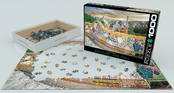 An assembled jigsaw puzzle featuring the vibrant designs of Barcelona's Park Güell, surrounded by scattered puzzle pieces. The box, labeled 'Barcelona - Park Güell', is displayed prominently next to the partially completed puzzle, showcasing colorful details inspired by Gaudí's iconic architecture.