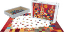 Castle and Sun by Paul Klee jigsaw puzzle from Eurographics. The puzzle features colorful abstract shapes, with a partially completed scene on a white surface. The box displays the artwork prominently, and loose pieces are arranged around it in a creative display.