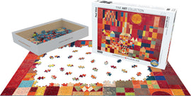 Castle and Sun by Paul Klee jigsaw puzzle from Eurographics. The puzzle features colorful abstract shapes, with a partially completed scene on a white surface. The box displays the artwork prominently, and loose pieces are arranged around it in a creative display.