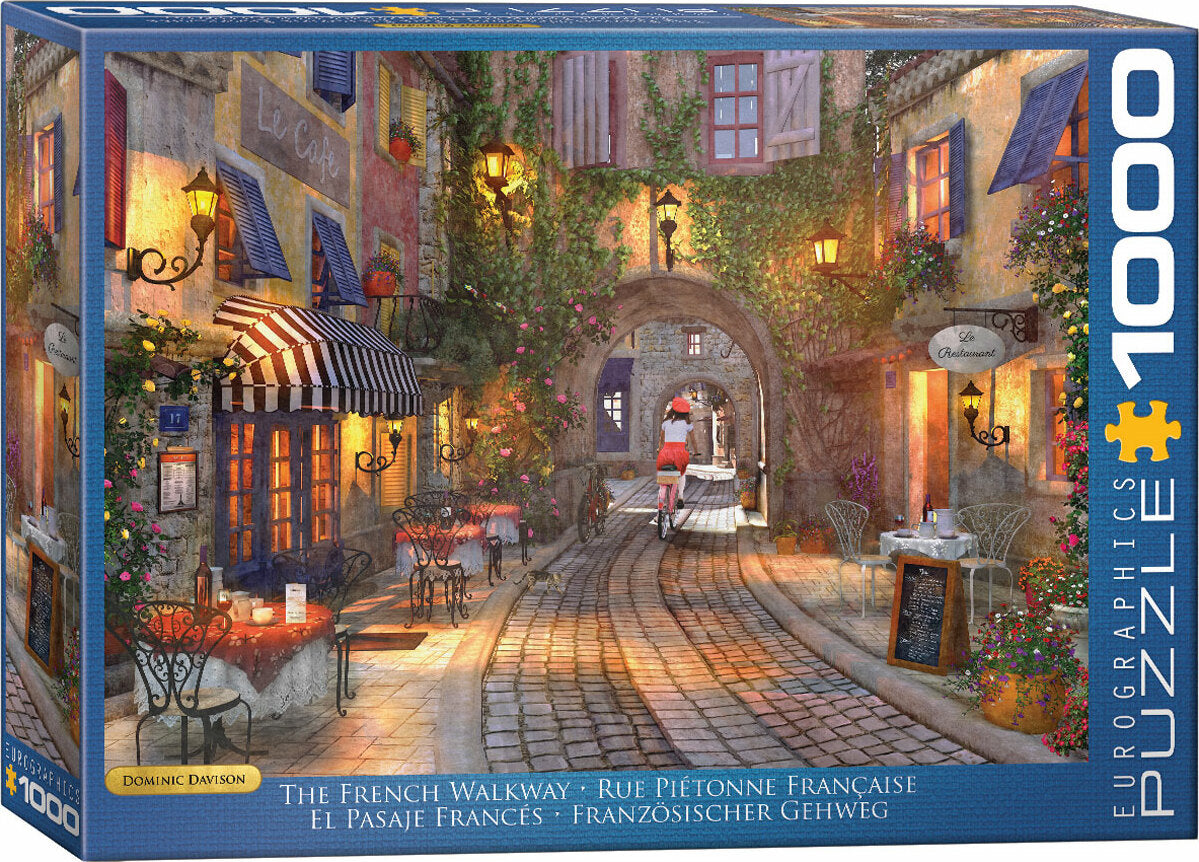 The French Walkway jigsaw puzzle by Dominic Davison showcases a charming street scene featuring cafes, blooming flowers, and a cyclist in a picturesque European town. The vibrant colors and intricate details invite puzzlers to immerse themselves in the scene, making it a delightful activity for art lovers.