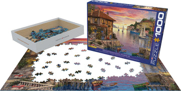 A 1000-piece jigsaw puzzle titled 'Mediterranean Harbor' by Dominic Davison, featuring a colorful coastal scene with boats, buildings, and a sunset. The pieces are scattered on a table, with the box displayed alongside.