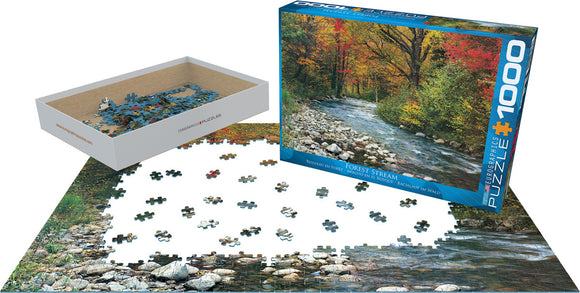 A 1000-piece jigsaw puzzle titled 'Forest Stream' by Eurographics, featuring a scenic view of a river surrounded by vibrant autumn trees. The pieces are scattered on a table, with the box displayed beside it, showcasing the completed image on the front.