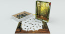 Eurographics Forest Path jigsaw puzzle featuring a serene scene of a wooded path with golden autumn leaves. The puzzle has 1000 pieces and is partially assembled, with many pieces visible in a white box beside the puzzle. The packaging showcases the lush green foliage of the forest path.