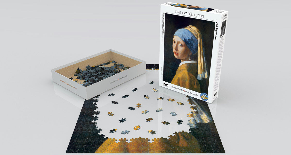 Eurographics jigsaw puzzle featuring 'Girl with the Pearl Earring', a famous painting by Jan Vermeer. The image shows the opened box with colorful puzzle pieces scattered on a flat surface, partially assembled puzzle depicting the artwork.