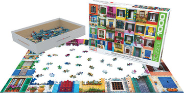 A jigsaw puzzle titled 'Mediterranean Windows' by Eurographics. The puzzle features vibrant images of various Mediterranean-style windows with colorful floral decorations. The box displays the completed image. In the foreground, pieces of the puzzle are scattered on a tabletop while the box is open, showcasing additional pieces inside.