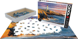Peggy's Cove Lighthouse jigsaw puzzle by Eurographics featuring 1000 pieces. The image depicts the iconic lighthouse against a coastal landscape. The puzzle pieces are scattered on a table, with the box displayed at the right, showcasing the beautiful artwork of the lighthouse and its rocky surroundings.