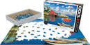 A 1000-piece jigsaw puzzle featuring a colorful scene of Peggy's Cove, Nova Scotia, including vibrant buildings, boats, and a clear sky. The puzzle pieces are spread out on a flat surface, with the box displayed next to them, showcasing the picturesque artwork on its front.