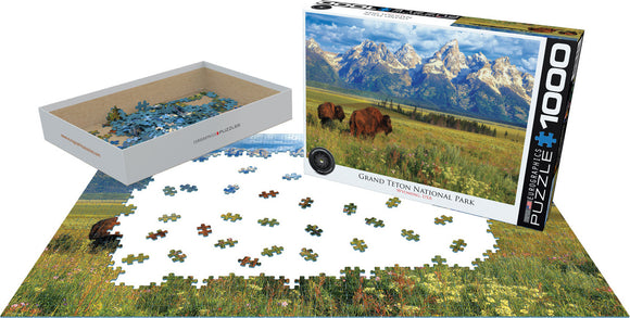 Grand Teton National Park jigsaw puzzle by Eurographics. The box displays a stunning picture of the mountains and bison in a grassy meadow. A portion of the puzzle is laid out on a flat surface, with various colorful pieces scattered around.