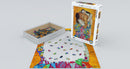 The Family jigsaw puzzle by Eurographics featuring an artistic image inspired by Gustav Klimt, showcasing colorful pieces scattered around the edge of the in-progress puzzle. The box is displayed next to the puzzle, highlighting the intricate art collection theme.