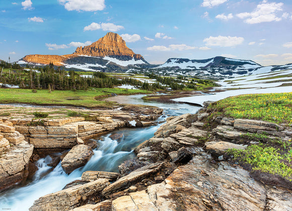Glacier National Park jigsaw puzzle by Eurographics, featuring a stunning landscape with a majestic mountain in the background, lush greenery, flowing water, and snow-capped peaks under a bright blue sky. Perfect for nature enthusiasts and puzzle lovers alike.