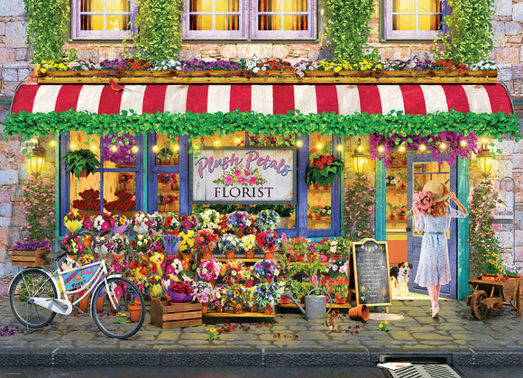 A vibrant jigsaw puzzle featuring a charming florist shop named 'Plush Petals'. The illustration showcases colorful flower displays and a woman wearing a sun hat, carrying a bouquet, walking toward the entrance. A bicycle is parked nearby, and a friendly dog watches from the open door, surrounded by lush greenery and warm lights.