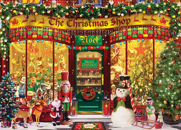 Eurographics The Christmas Shop jigsaw puzzle featuring a beautifully illustrated festive storefront. The scene includes a decorated Christmas shop with colorful lights, Christmas trees, and a variety of holiday decorations. Nutcrackers, snowmen, and reindeer are also depicted outside, creating a charming holiday atmosphere.