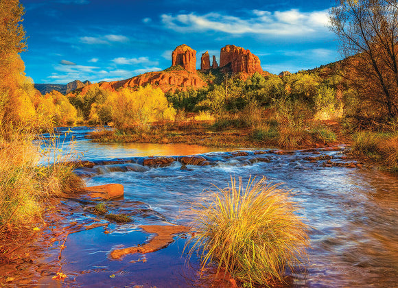 Red Rock Crossing jigsaw puzzle by Eurographics featuring a picturesque view of Arizona's stunning landscape with vibrant fall colors, flowing water, and striking rock formations under a blue sky, ideal for nature enthusiasts and puzzle lovers.
