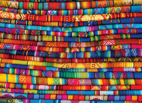 Colorful Peruvian blankets stacked together, showcasing intricate patterns and vibrant colors. The textiles feature a mix of geometric designs and traditional motifs that reflect Peruvian culture.