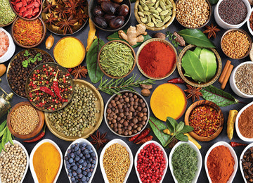 A vibrant, colorful arrangement of various spices and herbs displayed in bowls and dishes. The scene includes a variety of dried herbs, whole spices, and powders, showcasing a rich palette of colors like red, yellow, green, and brown. It captures the essence of culinary creativity and the joy of cooking with diverse flavors.