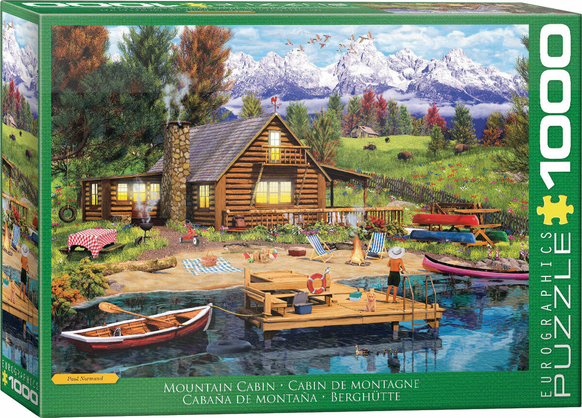 A colorful jigsaw puzzle box featuring a serene mountain cabin scene by Paul Normand. The illustration depicts a cozy log cabin by a lake, surrounded by trees and mountains. There are picnic tables, a canoe, and a dock with people relaxing and enjoying nature. Ideal for puzzle enthusiasts and nature lovers.