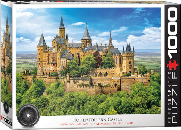 A beautifully illustrated jigsaw puzzle of Hohenzollern Castle in Germany, presented in a colorful box by Eurographics. The scene captures the majestic castle set amidst lush greenery and a bright blue sky, featuring turrets and intricate architectural details.