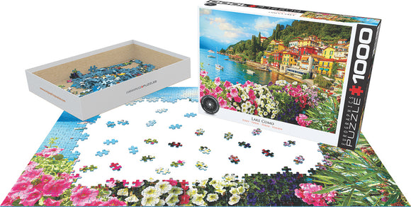 Eurographics jigsaw puzzle featuring a beautiful scene of Lake Como, Italy. The 1000-piece set includes vibrant flowers in the foreground and colorful buildings along the lakeshore, with pieces scattered and partially assembled.