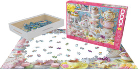 A EuroGraphics jigsaw puzzle titled "Tea Table," featuring a colorful, floral arrangement of teapots, teacups, and pastries. The partially completed puzzle displays intricate details and a vibrant design, with box and puzzle pieces in view.