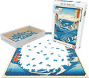 Eurographics Naruto Whirlpool jigsaw puzzle featuring intricate blue waves and a scenic landscape by Utagawa Hiroshige. The image showcases the 1000 pieces arranged partially completed, along with the box containing the remaining pieces, emphasizing its artistic detail and vibrant colors.