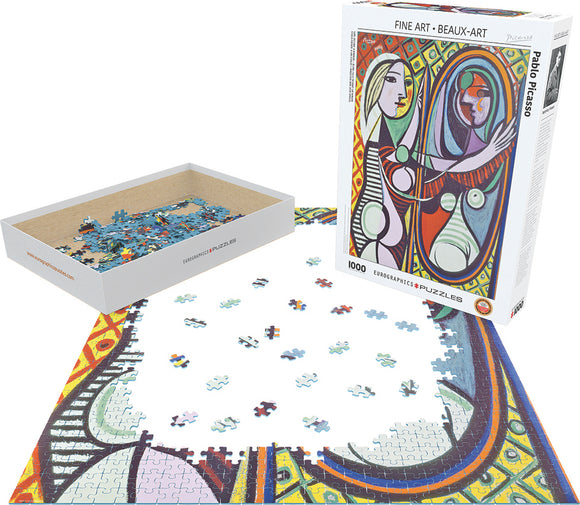A 1000-piece jigsaw puzzle featuring 'Girl Before a Mirror' by Pablo Picasso. The image shows scattered puzzle pieces on a table alongside the puzzle box, which showcases the colorful artwork by Picasso. The puzzle pieces vary in shades of blue, red, and green, ready to be assembled into the richly detailed artwork.