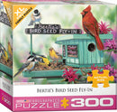 Bertie's Bird Seed Fly-In jigsaw puzzle box featuring colorful artwork by Janene Grende. The image depicts a variety of birds at a bird feeder, surrounded by vibrant flowers. The puzzle contains 300 XL pieces, ideal for family fun.