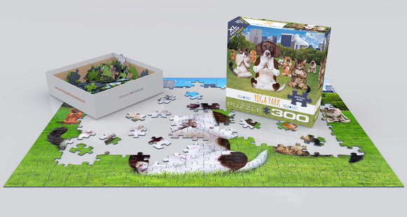 The Yoga Park jigsaw puzzle by Eurographics features a vibrant scene depicting adorable animals, including dogs and cats, practicing yoga in a green park. The image shows some pieces of the puzzle on a table, with the puzzle box displayed prominently in the background.