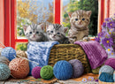 A charming jigsaw puzzle featuring three adorable kittens nestled in a woven basket, surrounded by colorful yarn balls and a cozy knit blanket. The scene is framed by a bright red window and vibrant flowers, creating a warm and inviting atmosphere perfect for cat lovers and puzzle enthusiasts alike.