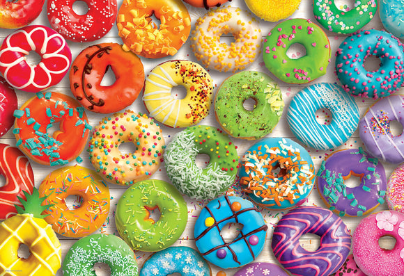 A vibrant collection of colorful, decorated donuts displayed in a visually appealing arrangement. The donuts feature various toppings like sprinkles, icing, and fruit slices in a rainbow of colors, creating a fun and eye-catching jigsaw puzzle image.
