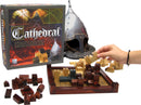 Cathedral game by Family Games Inc. featuring a medieval strategy board game. The image shows the game box, wooden building pieces in various colors, and a player placing a piece on the board, which has a checkerboard grid design. A knight helmet is displayed in the background, enhancing the medieval theme.
