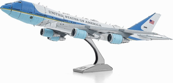A detailed metal model of Air Force One, showcasing its iconic blue and white color scheme, with the words 'United States of America' on the fuselage. The model is displayed on a sturdy base, highlighting the aircraft's sleek design and three prominent engines.