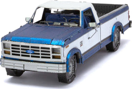 A detailed metal model kit of a 1982 Ford F-150 by Fascinations. The model features a blue and white exterior with intricate design elements, showcasing realistic details like windows, wheels, and a truck bed. Perfect for DIY enthusiasts and collectors alike.