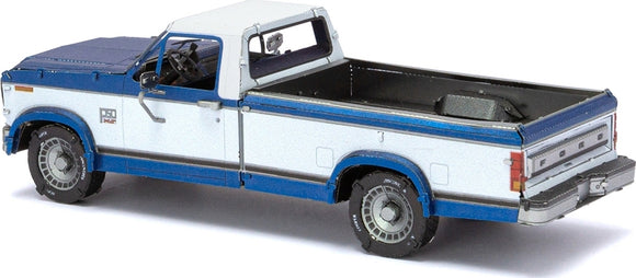 A detailed model kit of a 1982 Ford F-150 pickup truck by Fascinations. The model features a two-tone blue and white exterior, intricate detailing on the wheels, and an open truck bed, making it a perfect DIY project for automotive enthusiasts.