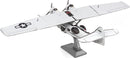 Detailed model of a Consolidated PBY Catalina airplane from Metal Earth by Fascinations. The kit features intricate metal parts with a realistic design, showcasing a sleek white fuselage and black insignia. It stands on a sturdy base, highlighting the aircraft's unique twin-engine configuration and wide wingspan, ideal for aviation enthusiasts and hobbyists.