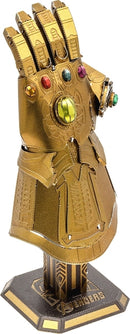 Metal Earth: Infinity Gauntlet DIY kit by Fascinations featuring intricate details and vibrant colored gems. This model depicts the iconic Marvel glove with gold finish and stands on a hexagonal base, perfect for display.
