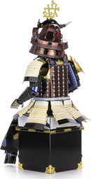 A detailed metal model of a Samurai Armor. The intricate design features vibrant colors including bronze, gold, and black, showcasing traditional armor details like layered plates, a helmet with a decorative crest, and an elaborate base. This DIY kit by Fascinations allows for an engaging building experience that results in a stunning display piece.