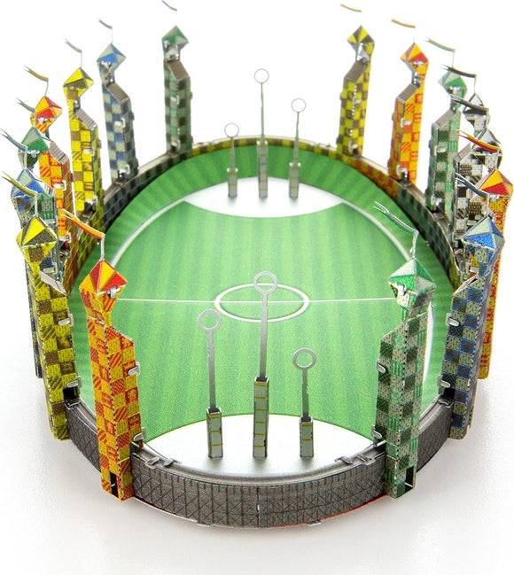 A detailed Metal Earth Quidditch Pitch DIY model showcasing a vibrant green field surrounded by colorful towers with flag-topped spires. The three goal hoops are positioned in the center, highlighting the classic design of the iconic wizarding sport venue.