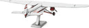 A detailed Metal Earth DIY kit of a Ford Trimotor airplane, showcasing intricate metal parts and a finely crafted design. The model is displayed on a stand, highlighting its vintage features and accurate proportions.
