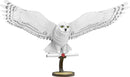 Premium S: Hedwig DIY kit by Fascinations. Features an intricately designed snowy owl with wings spread wide, perched on a rustic-looking stand. The owl is detailed with textured feathers and striking yellow eyes, enhancing its majestic appearance, perfect for display.