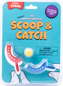 Teeny Town Scoop and Catch game, which includes two colorful scoops in red and blue, and a small yellow ball for coordination challenges. The packaging displays the playful design and a warning about choking hazards, emphasizing the game's engaging and fun nature.