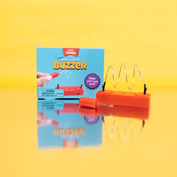 The Teeny Town Buzzer Game by Fizz Creations Inc. features a colorful box with instructions and a buzzer with a curved wire. The product encourages creativity by enabling users to shape their own wire while having fun.