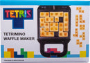 A Tetris-themed waffle maker designed by Fizz Creations Inc. The appliance features a black exterior with a grid for making waffles shaped like Tetriminos, iconic blocks from the Tetris game. Surrounding the waffle maker are several golden-brown Tetrimino-shaped waffles, highlighting its unique design.