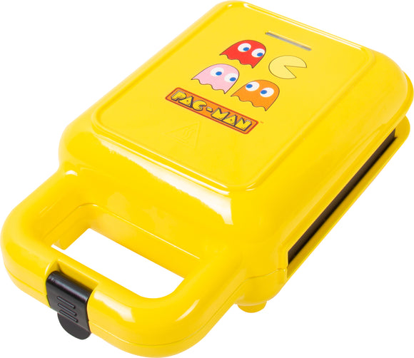 A vibrant yellow Pac Man Waffle Maker featuring the iconic Pac Man character and colorful ghosts. The device has a sturdy handle for easy operation and is designed to create fun, Pac Man-shaped waffles, ideal for gaming enthusiasts and breakfast lovers alike.