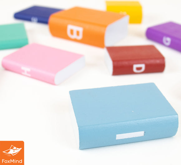A collection of colorful miniature books in various shapes and sizes, displayed on a light background. The books feature different colors including blue, pink, orange, and purple, each with simple designs on their spines, making them visually appealing and fun for display or use in activities.