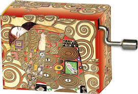 A colorful music box featuring the artwork 'The Embrace' by Klimt. The box is intricately designed with swirling patterns and vibrant colors. It showcases a romantic scene with characteristic golden hues and decorative motifs common in Klimt's style. The winding handle is visible on the side.