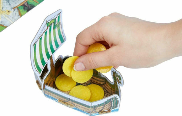 A hand reaching into a colorful cardboard Viking ship, retrieving yellow token coins. The ship features green and white stripes on the sail and decorative designs, highlighting a playful, engaging game experience inspired by the theme 'Valley of the Vikings' by Haba.