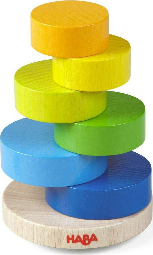 Colorful wooden stacking game featuring circular discs in yellow, green, blue, and orange, all sitting on a round wooden base with the Haba logo. Ideal for enhancing fine motor skills and hand-eye coordination in children.