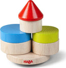 Wobbly Tower stacking game made by HABA featuring colorful wooden pieces including a red cone, green, blue, and natural wood discs, designed to promote fine motor skills and balance.