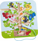 The Magnetic Game Orchard by Haba features a colorful tree with fruit and playful animals. A magnetic rod is used to maneuver small colored balls through the tree's winding pathways, promoting fine motor skills and hand-eye coordination in young children.
