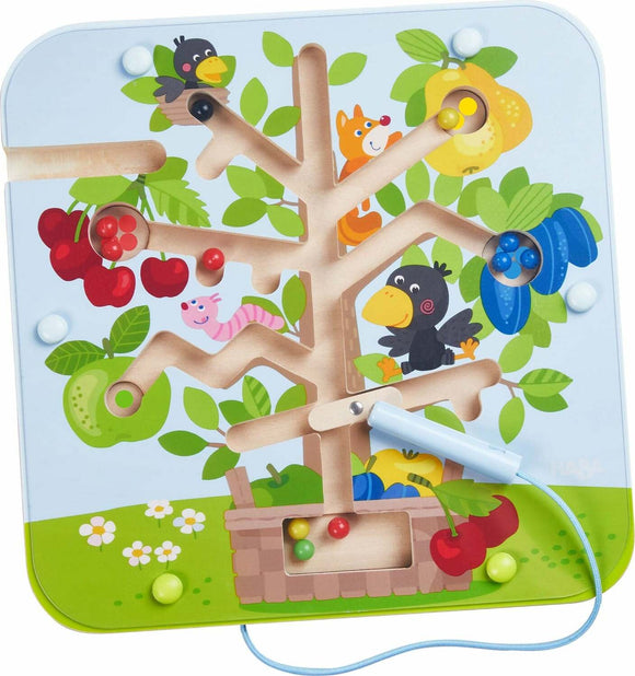The Magnetic Game Orchard by Haba features a colorful tree with fruit and playful animals. A magnetic rod is used to maneuver small colored balls through the tree's winding pathways, promoting fine motor skills and hand-eye coordination in young children.